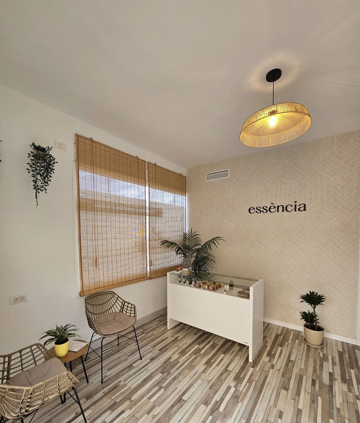 Entrada y mostrador de Essència, con el logotipo de la marca en la pared